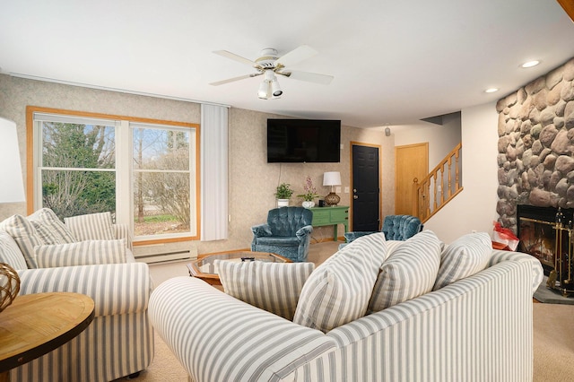 living room with carpet flooring, ceiling fan, a fireplace, and a baseboard radiator