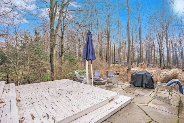 wooden terrace with an outdoor fire pit, grilling area, and a patio area