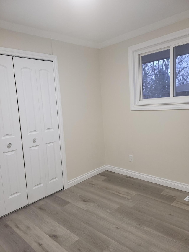 unfurnished bedroom featuring light hardwood / wood-style flooring, a closet, and ornamental molding