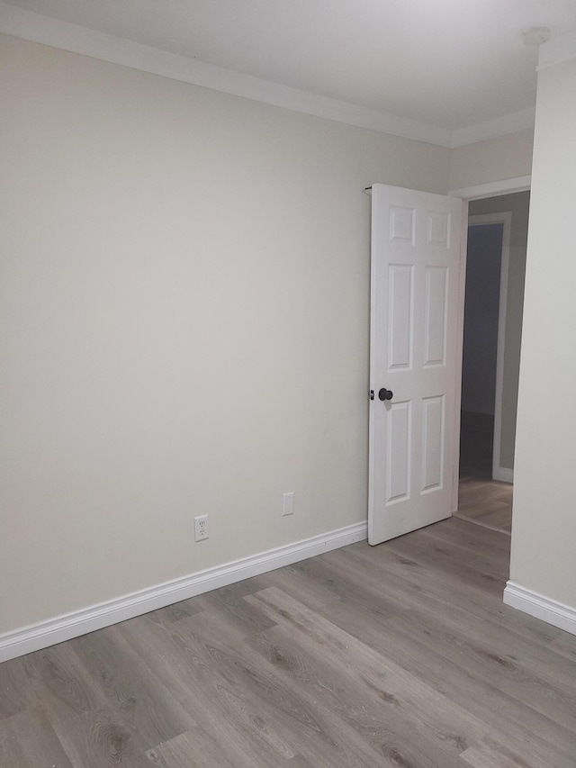 empty room with light hardwood / wood-style floors and ornamental molding