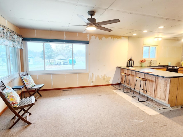 living area with ceiling fan, a healthy amount of sunlight, sink, and light carpet