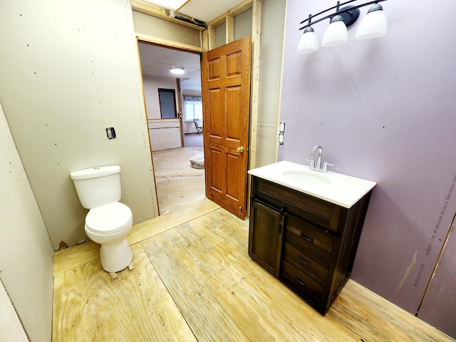 bathroom featuring vanity, wood-type flooring, and toilet