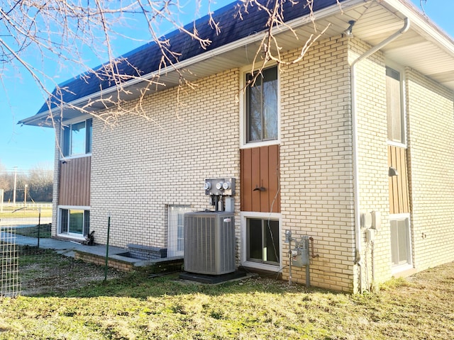 view of side of property featuring central AC unit and a yard