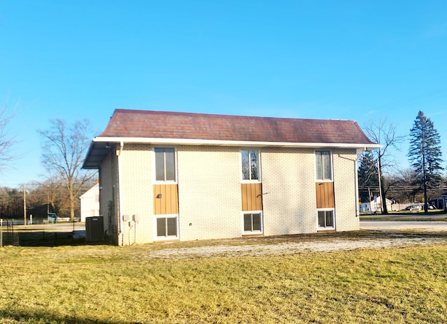 back of house with central AC and a lawn