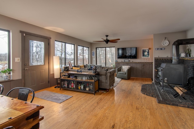 living room featuring ceiling fan, a wood stove, and light hardwood / wood-style flooring