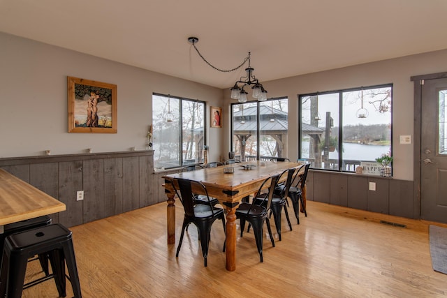 dining room with light hardwood / wood-style floors, a water view, and a chandelier