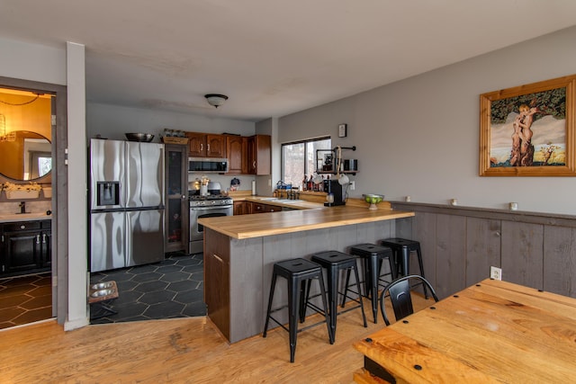 kitchen with a kitchen breakfast bar, light wood-type flooring, kitchen peninsula, and stainless steel appliances