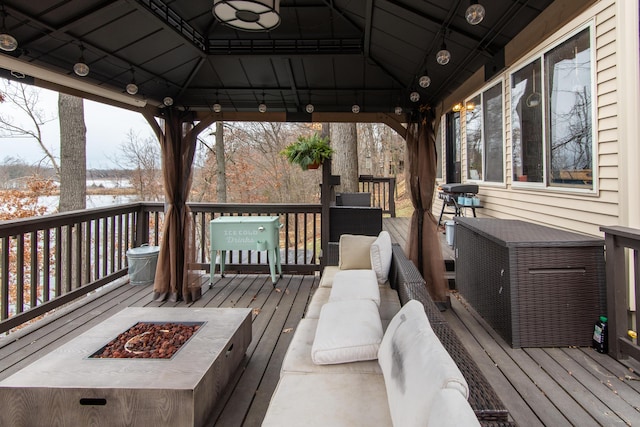 wooden deck featuring a gazebo and a fire pit