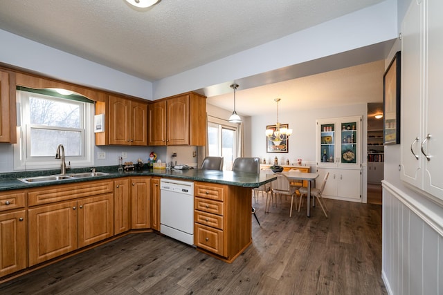 kitchen with dishwasher, sink, decorative light fixtures, dark hardwood / wood-style flooring, and kitchen peninsula