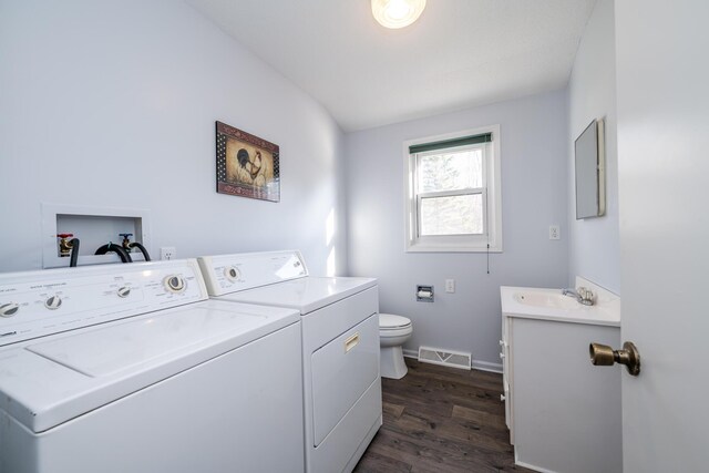 washroom featuring dark hardwood / wood-style flooring, washing machine and dryer, and sink