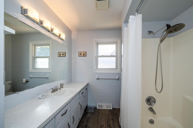 bathroom featuring vanity, shower / bathtub combination with curtain, tile walls, and a wealth of natural light