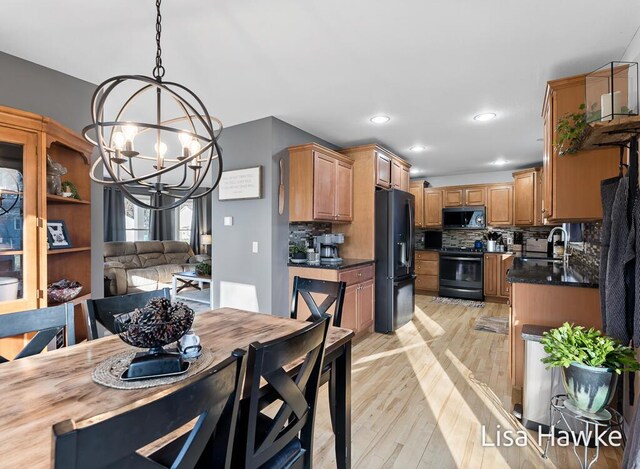 dining space with light hardwood / wood-style floors, a notable chandelier, and sink