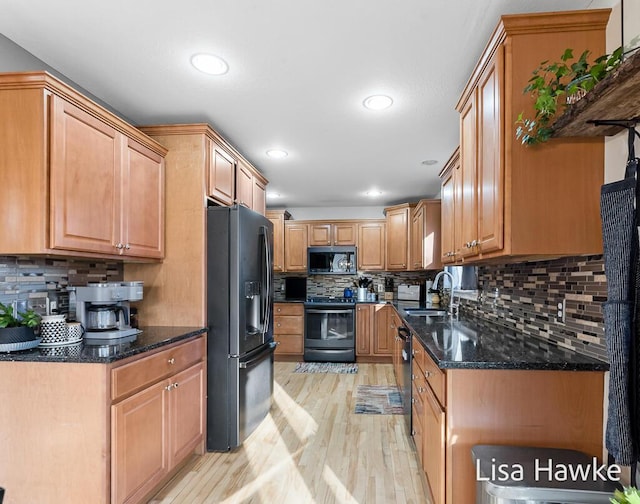 kitchen featuring dark stone counters, black appliances, sink, light hardwood / wood-style flooring, and tasteful backsplash