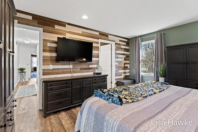 bedroom with light hardwood / wood-style flooring and wooden walls