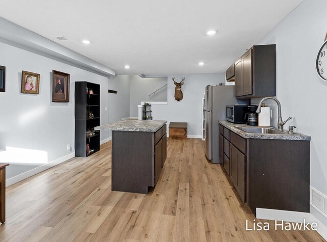 kitchen featuring sink, a kitchen island, dark brown cabinets, and light hardwood / wood-style flooring