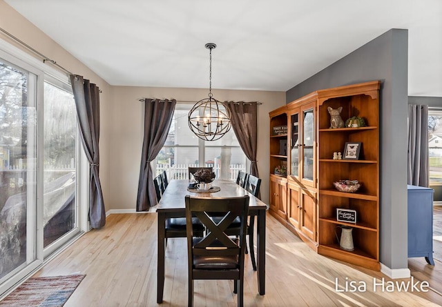 dining area with light hardwood / wood-style floors and an inviting chandelier