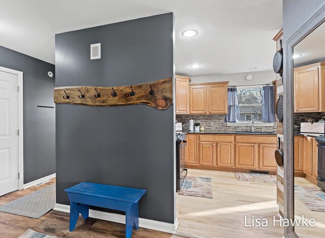 kitchen featuring black / electric stove, decorative backsplash, sink, and light wood-type flooring