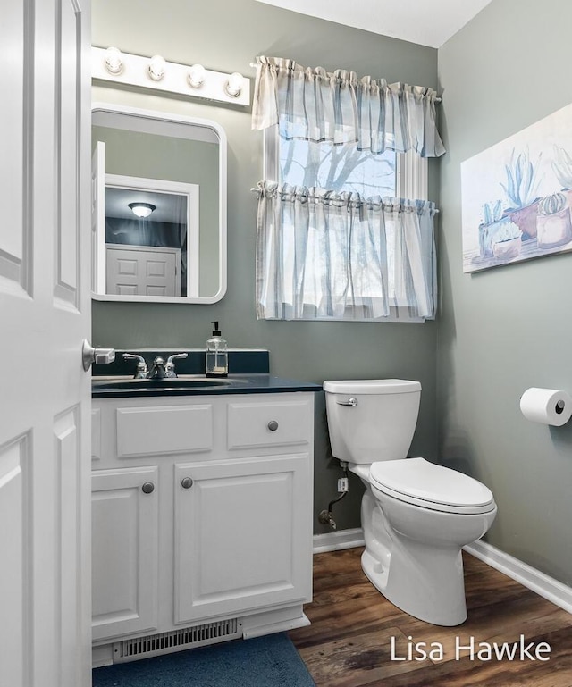 bathroom featuring wood-type flooring, vanity, and toilet