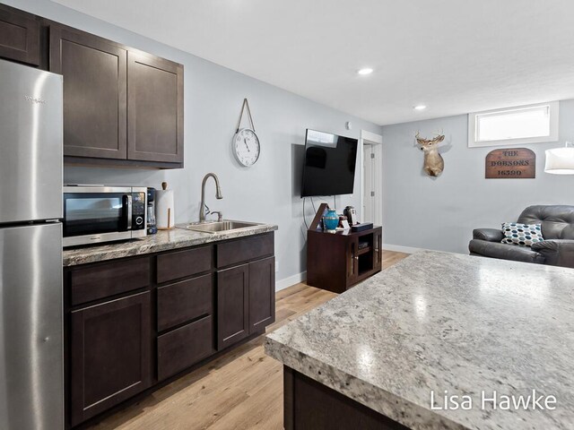 kitchen featuring sink, stainless steel appliances, dark brown cabinets, and light hardwood / wood-style flooring