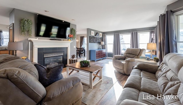 living room featuring a tile fireplace and light wood-type flooring