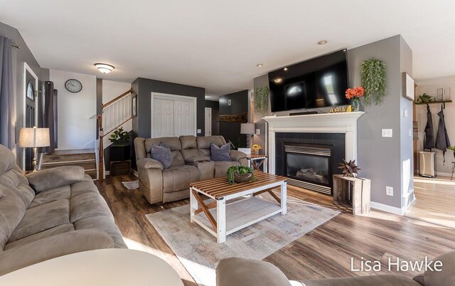 living room with a tile fireplace and hardwood / wood-style floors