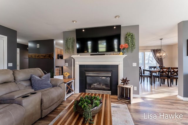 living room featuring wood-type flooring, a fireplace, and an inviting chandelier