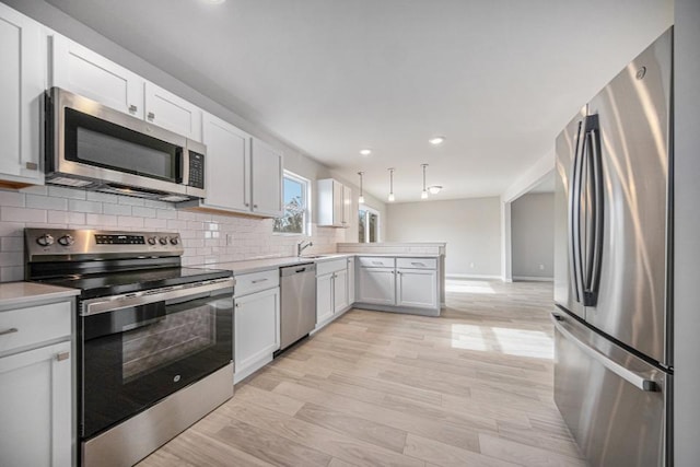 kitchen featuring backsplash, light wood-type flooring, white cabinets, and appliances with stainless steel finishes