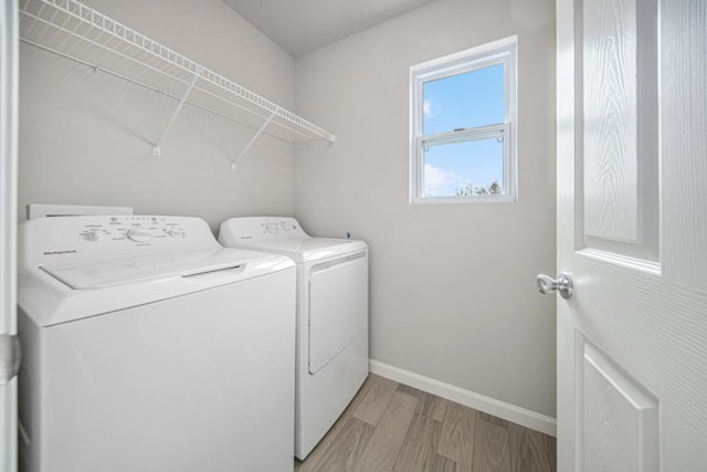 clothes washing area featuring washer and clothes dryer and light hardwood / wood-style floors