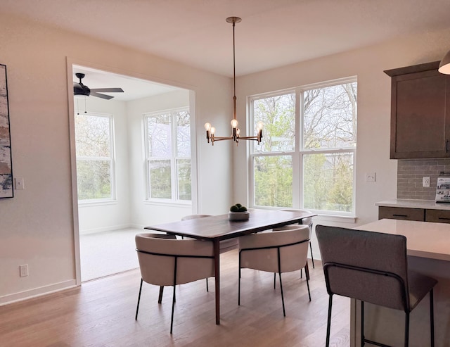 dining space featuring a wealth of natural light, light wood-style flooring, baseboards, and ceiling fan with notable chandelier