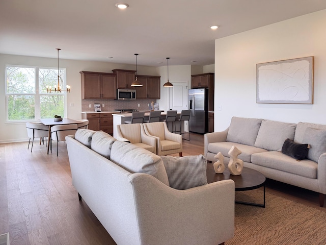 living room featuring baseboards, recessed lighting, a chandelier, and light wood-type flooring