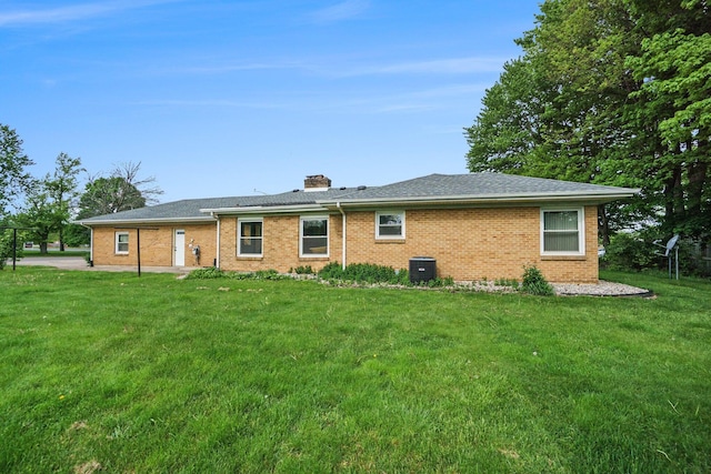 rear view of property featuring cooling unit and a yard