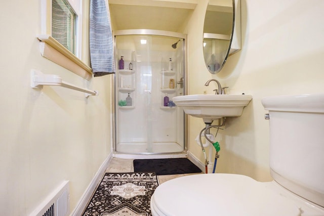 bathroom featuring sink, a shower with door, and toilet