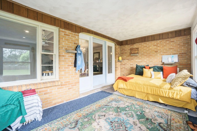 bedroom with wood walls, crown molding, and brick wall