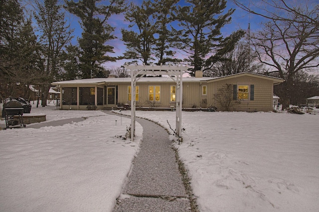 snow covered back of property featuring a sunroom and a pergola