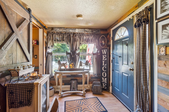 foyer entrance featuring a barn door, a textured ceiling, and light wood-type flooring