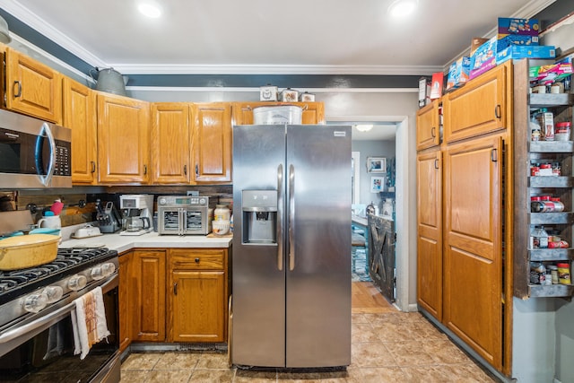 kitchen with appliances with stainless steel finishes, light tile patterned floors, and crown molding