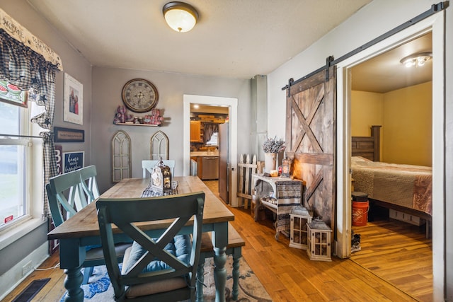 dining area with a barn door and hardwood / wood-style flooring