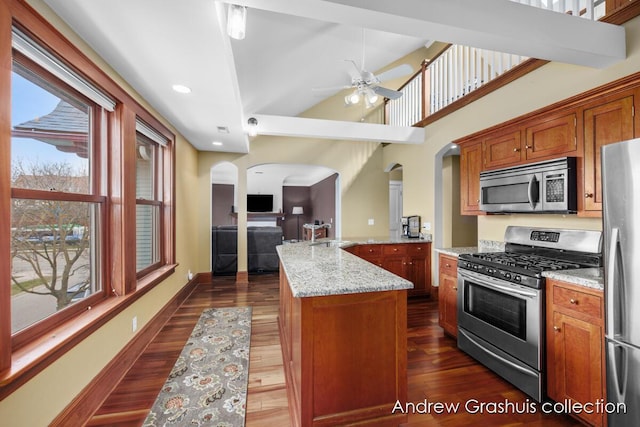 kitchen featuring light stone counters, a kitchen island with sink, appliances with stainless steel finishes, and dark wood-type flooring