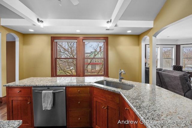 kitchen featuring beam ceiling, light stone countertops, dishwasher, sink, and plenty of natural light