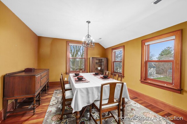 dining space with vaulted ceiling, light hardwood / wood-style flooring, and an inviting chandelier