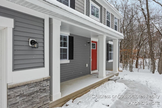 snow covered property entrance with covered porch