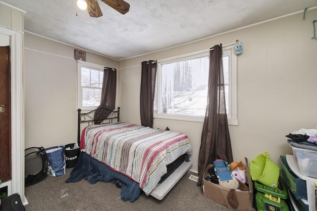 bedroom with a textured ceiling, carpet floors, ceiling fan, and multiple windows