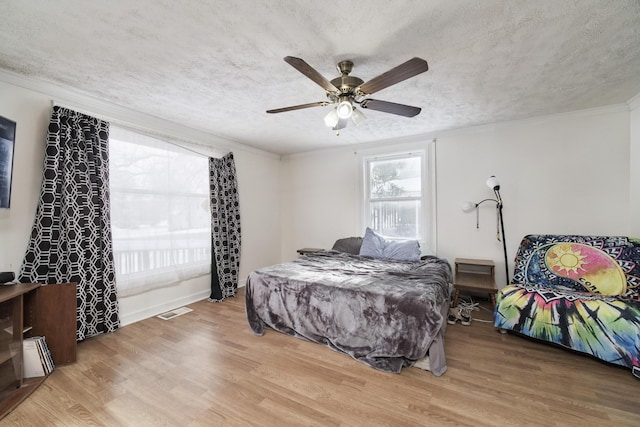 bedroom featuring hardwood / wood-style floors, a textured ceiling, ceiling fan, and ornamental molding