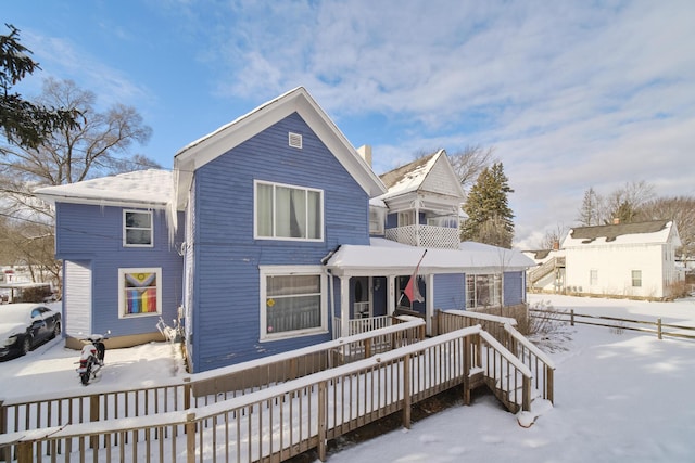 snow covered rear of property featuring covered porch