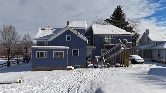 snow covered rear of property with a wooden deck