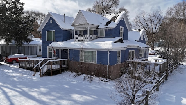 snow covered back of property featuring a deck