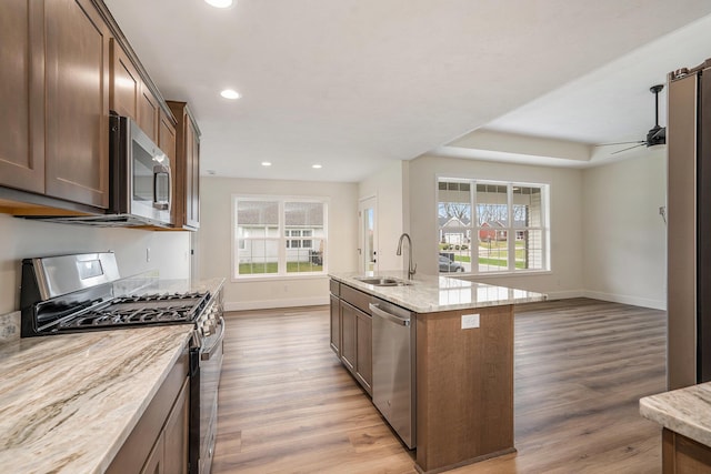 kitchen with light wood finished floors, recessed lighting, appliances with stainless steel finishes, a sink, and light stone counters