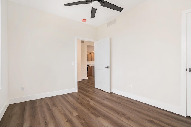 spare room with baseboards, visible vents, a ceiling fan, and wood finished floors