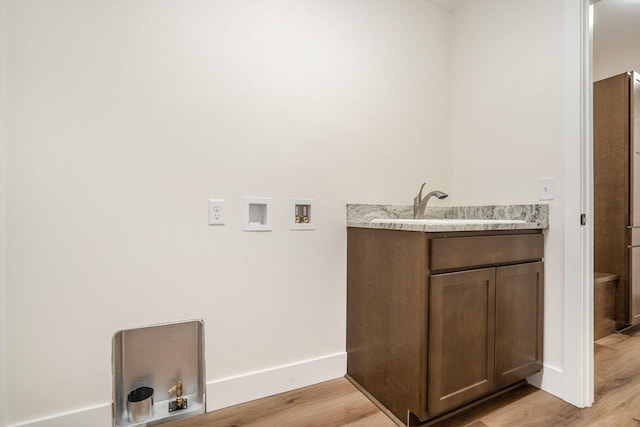 clothes washing area with washer hookup, baseboards, light wood-style flooring, and a sink