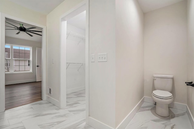 bathroom with toilet, marble finish floor, baseboards, visible vents, and ceiling fan